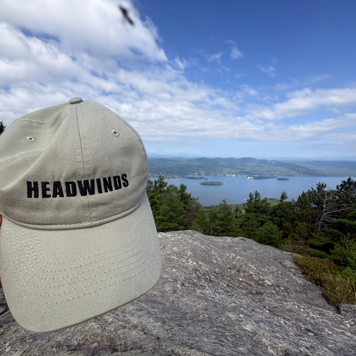 The Trailhead Cap held up at the summit against sky and lake