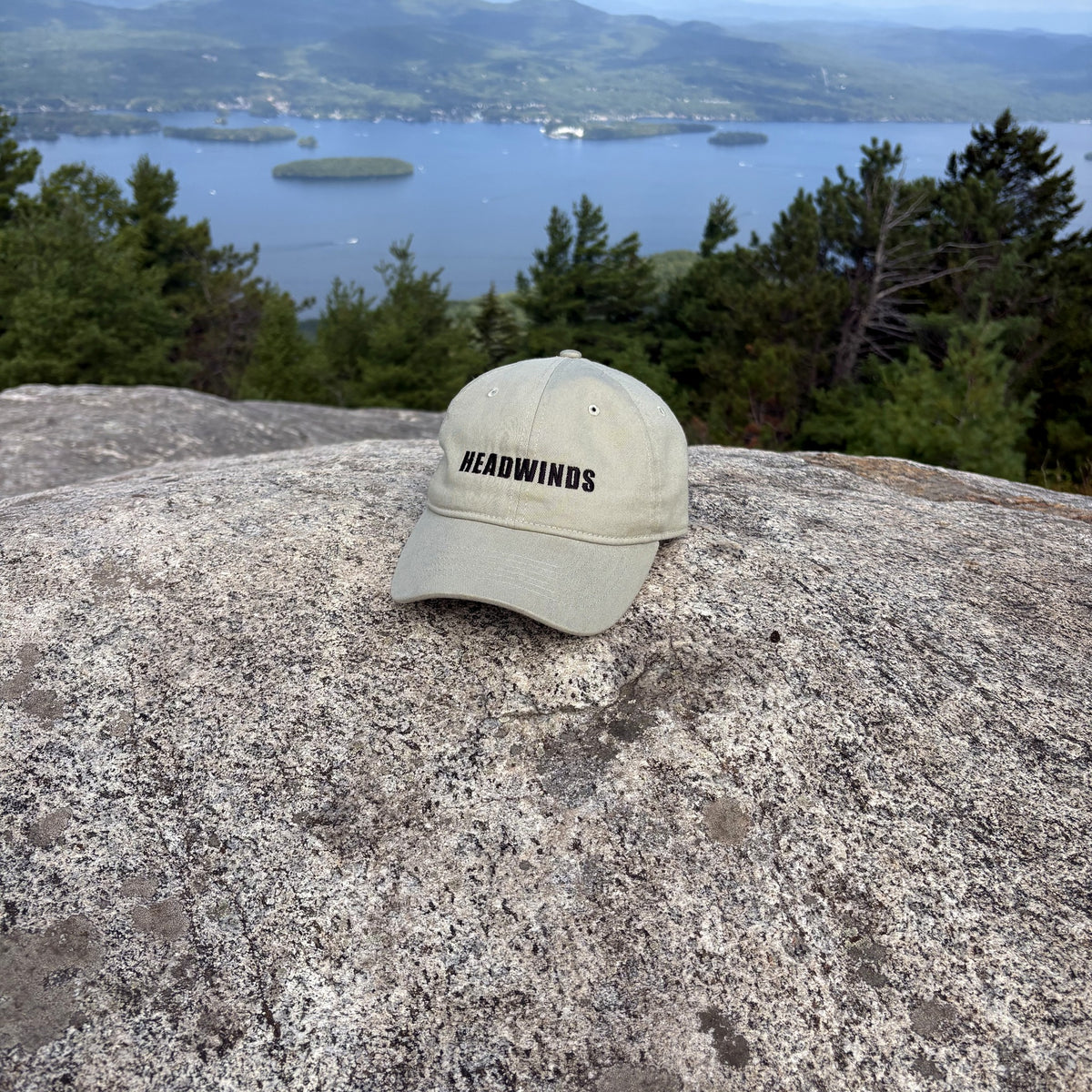 The Trailhead Cap on granite at the Buck Mountain summit, Lake George behind