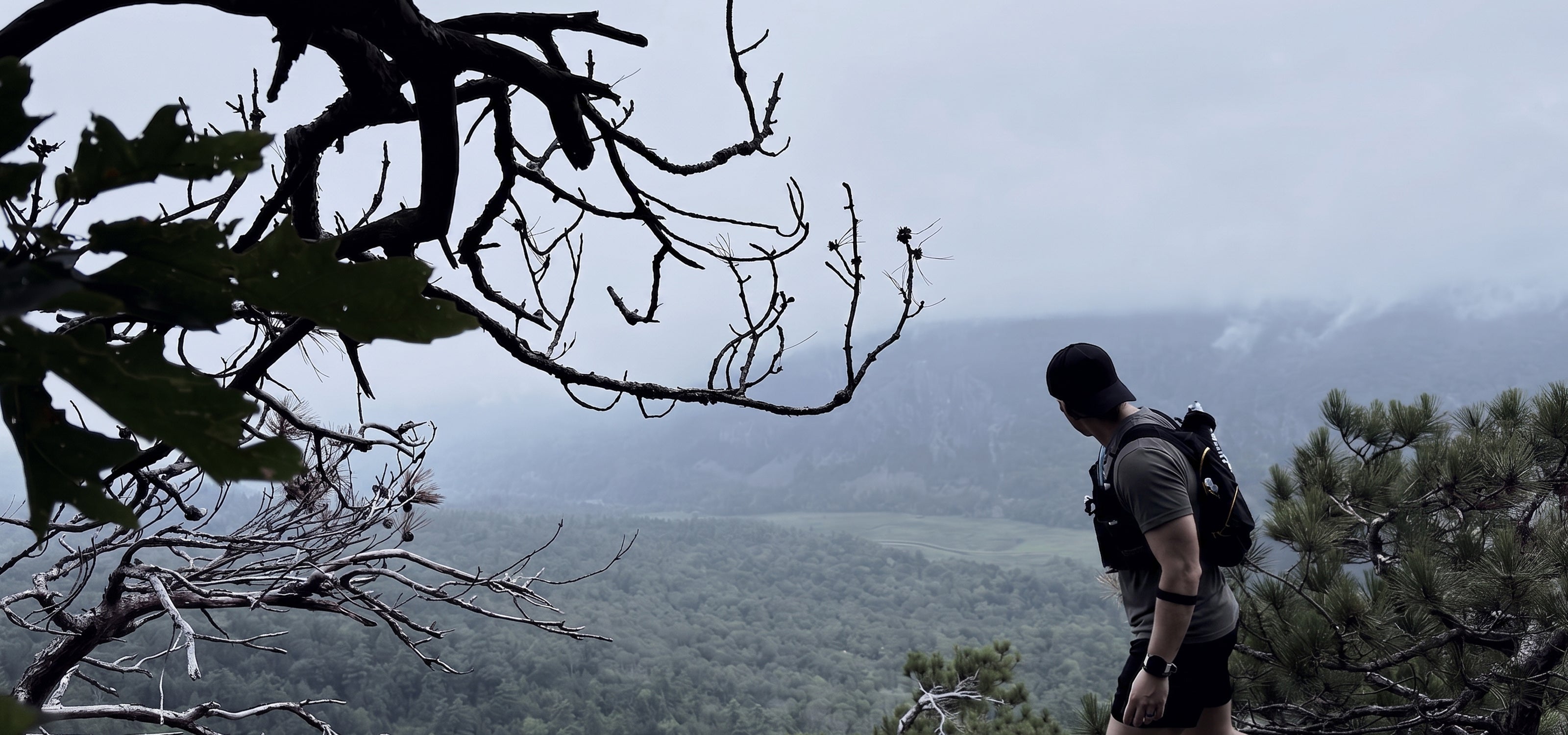 Trail runner on an exposed ledge in low cloud